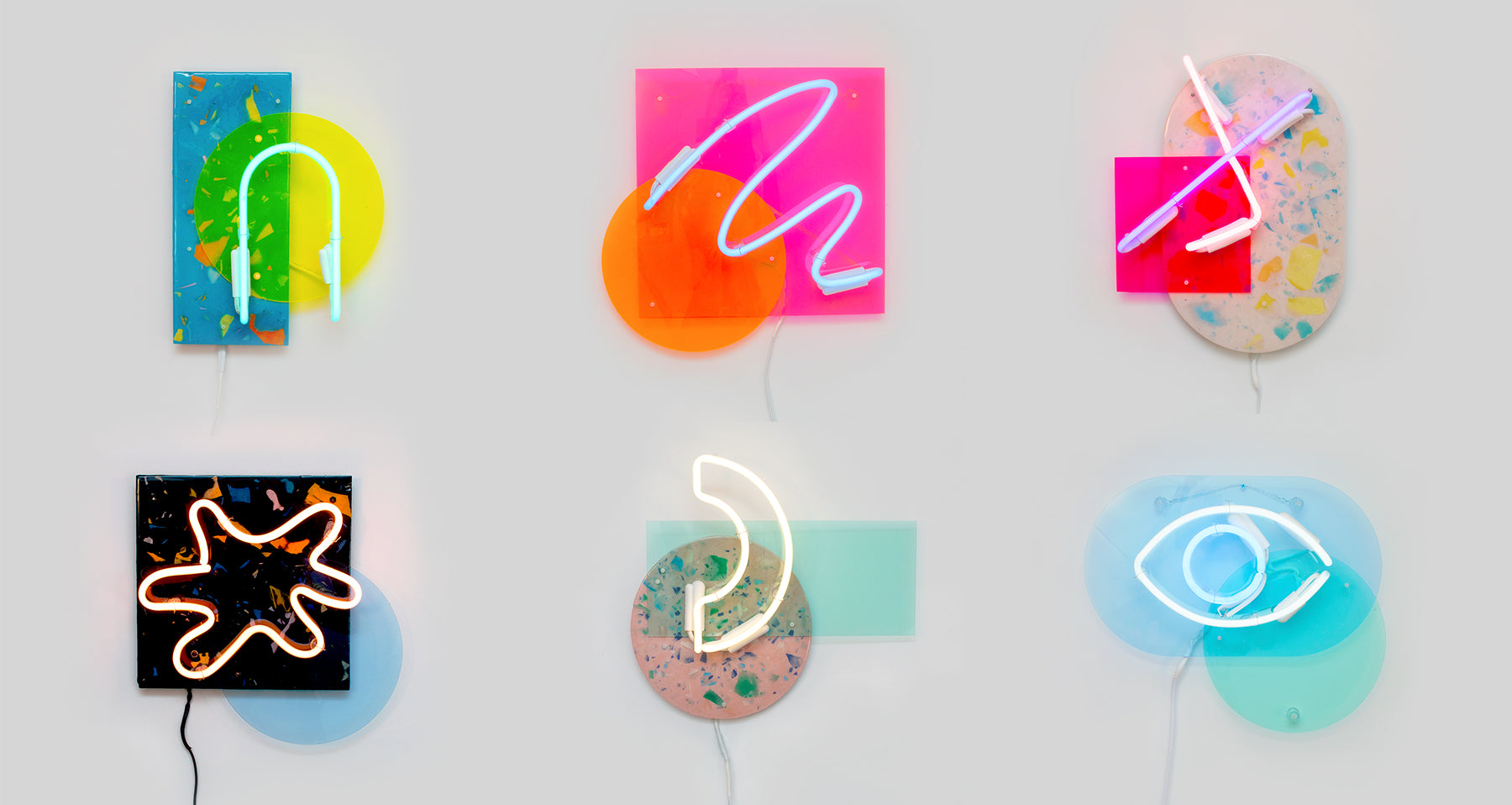 6 Neon light artworks hanging on a white wall. There are different color combinations each, using Glass neon, acrylic and terrazzo. 